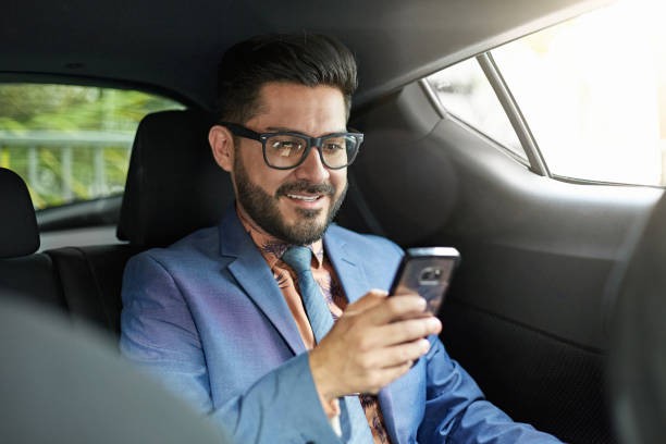 istock Hispanic Businessman Checking Smart Phone in Car Back Seat 1276803978