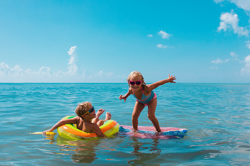 Little boy and girl swimming, splashing and playing in the sea with inflatable ring