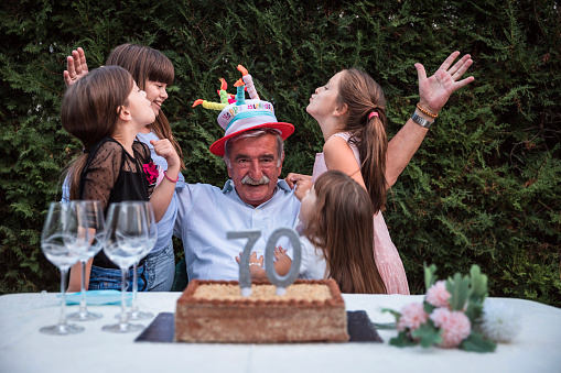 Senior man having 70th birthday party with grandchildren