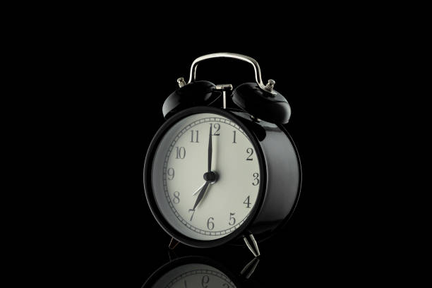 istock Black alarm clock isolated on a black background. 1276809984