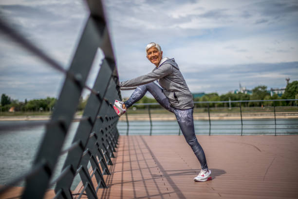 istock Active senior woman warming up by the river for jogging 1276810002