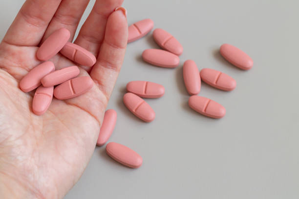 mano femenina sosteniendo píldoras rosas - pink pill fotografías e imágenes de stock