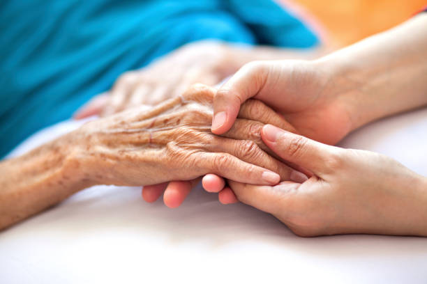 Helping the needy Woman holding senior woman's hand on bed seniors stock pictures, royalty-free photos & images