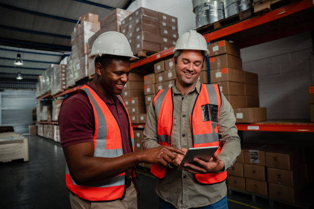 istock Smiling workers browsing on digital tablet watching funny videos standing in factory 1276815524
