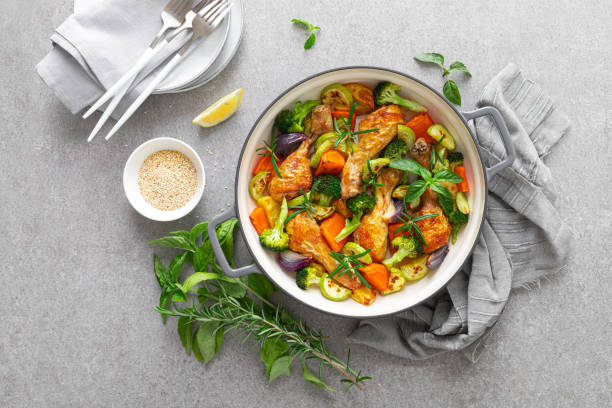 baquetas de frango assadas com legumes em panela de ferro fundido na mesa da cozinha, vista para baixo - animal skin prepared potato chicken leg chicken - fotografias e filmes do acervo