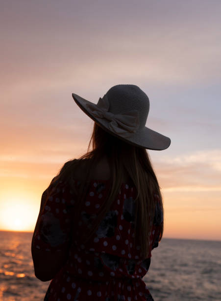 istock Young woman in hat standing on sand and looking to a sky 1276817021