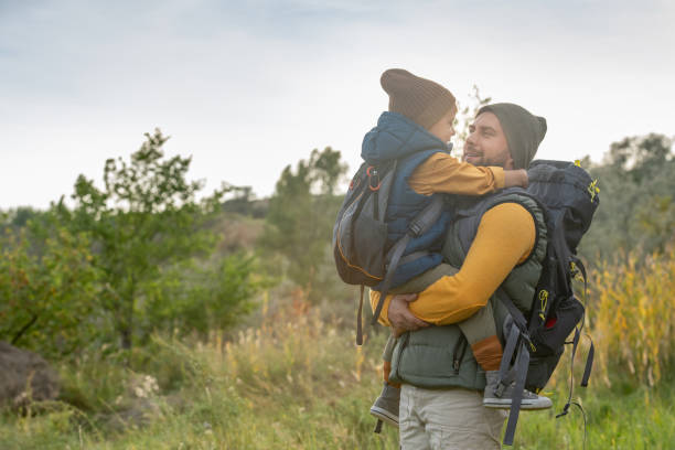 istock Young affectionate father with backpack holdng his cute little son on hands 1276820018