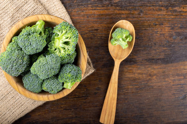Fresh broccoli with in bowl on wooden table close up. Fresh broccoli with in bowl on wooden table close up. Fiber-rich food. broccoli crowns stock pictures, royalty-free photos & images