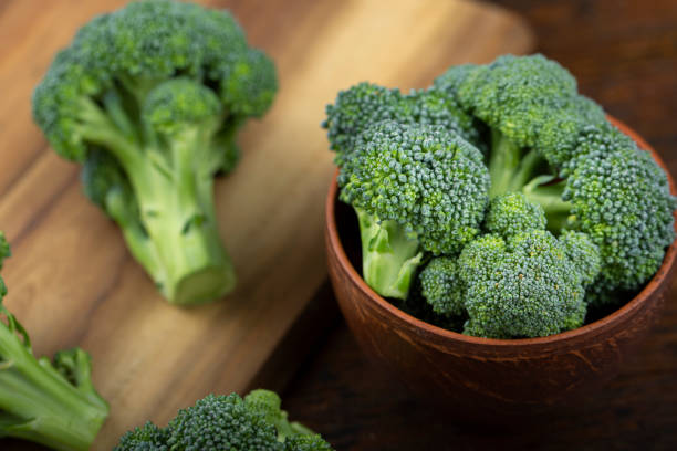 Bunch of fresh green broccoli Bunch of fresh green broccoli on clay plate over wooden background. broccoli crowns stock pictures, royalty-free photos & images