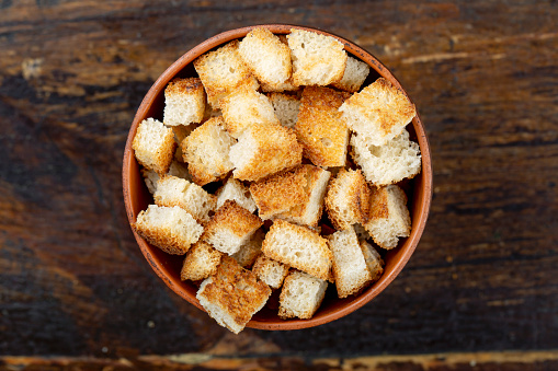 croutons beer snack crackers in a plate on a brown wooden background. view from above