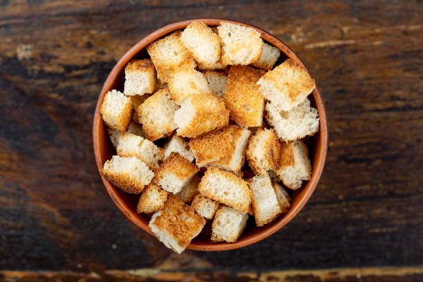 croutons biscoitos de cerveja em um prato em um fundo de madeira marrom. - cereais de pequeno almoço - fotografias e filmes do acervo