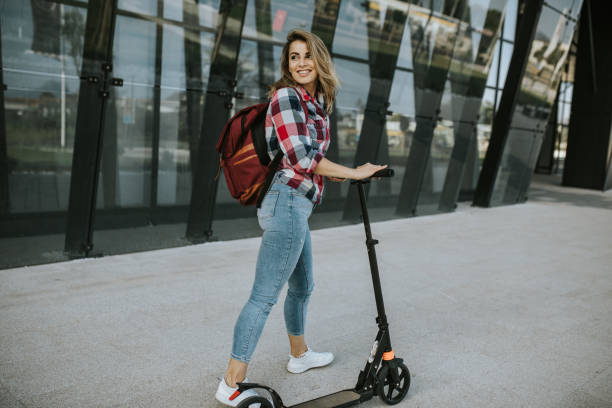 istock Female student with push scooter walking in front of university 1276825482