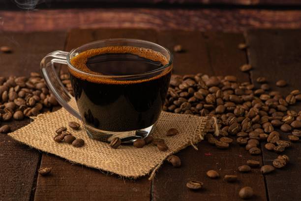 café negro servido en una taza trasparente de vidrio con granos de café alrededor - coffee black coffee cup coffee bean fotografías e imágenes de stock