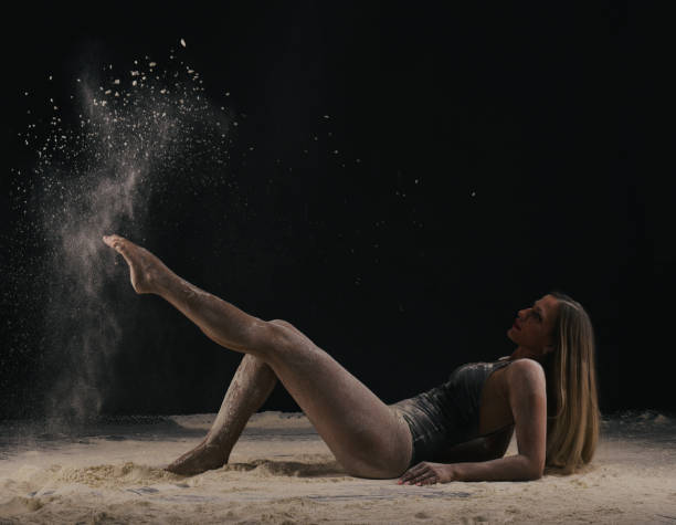 istock Dancer with long blond hair throwing dust, flour, powder on black background. 1276831629