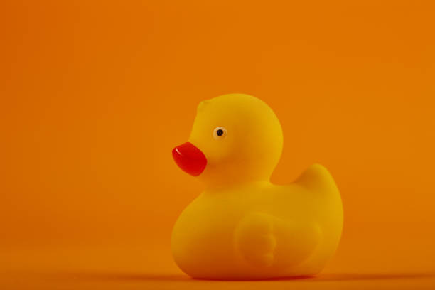 istock Yellow rubber duck toy on orange / yellow background 1276833963
