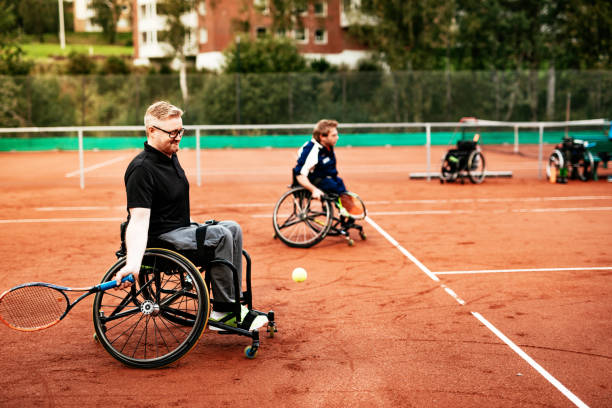 Men in wheelchair playing tennis outdoors Men in wheelchair playing tennis and conquer adversity wheelchair tennis stock pictures, royalty-free photos & images