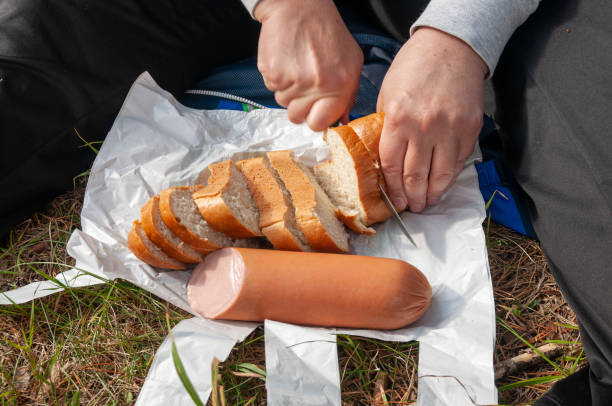 режет булочку и колбасу на полиэтиленовый пакет - bakery meat bread carbohydrate стоковые фото и изображения