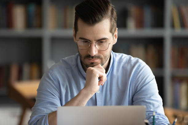 istock Pensive young man look at laptop screen working at home 1276837757