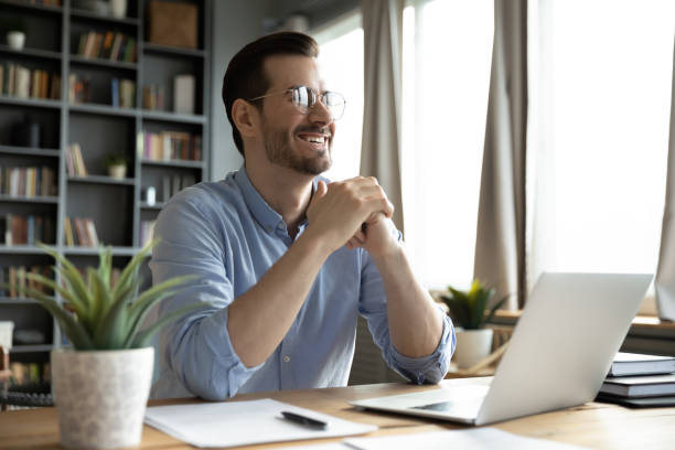 istock Smiling man distracted form laptop dreaming of success 1276837765