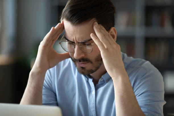 istock Unwell young man suffering from headache at workplace 1276837787