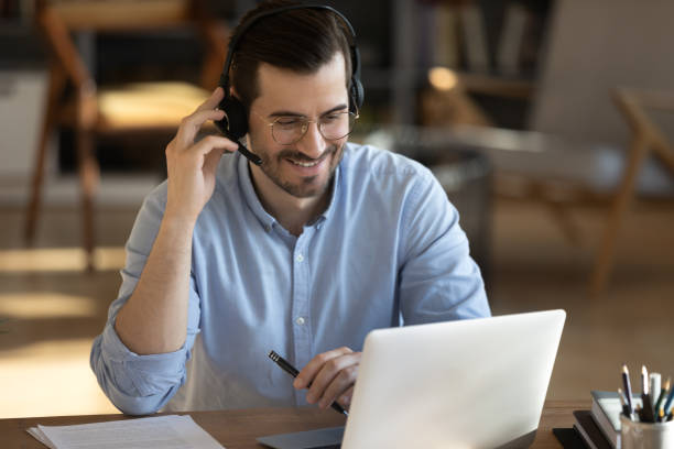 istock Smiling Caucasian man in headphones work on laptop 1276837795