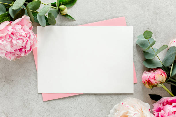 istock Mockup invitation, blank paper greeting card, pink envelope and peonies on gray stone table. Flower background. Flat lay, top view 1276838701
