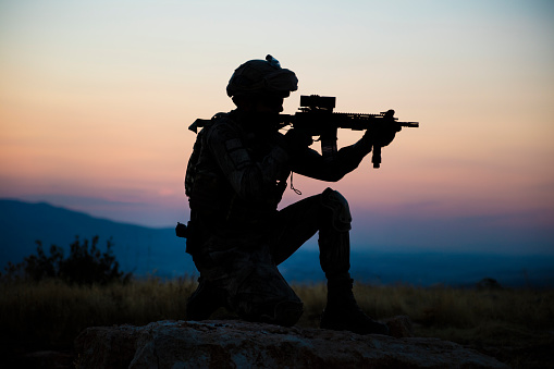 Silhouette of an kneeling Turkish soldier shooting at target at sunset