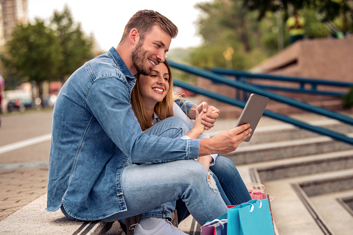 Happy couple with shopping bags taking selfie with smart phone.