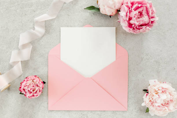 istock Mockup invitation, blank paper greeting card, pink envelope and peonies on gray stone table. Flower background. Flat lay, top view 1276840811