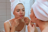 The girl squeezes out a pimple, looking in the mirror, in the bathroom