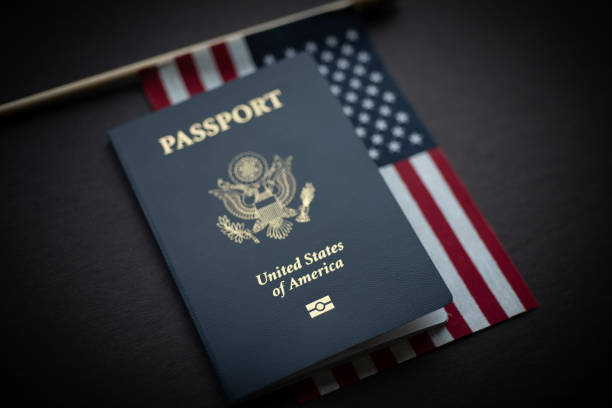 American Flag under Passport of USA. Black Background. American Flag covered with Passport of USA on Dark surface. blue us passport cover stock pictures, royalty-free photos & images
