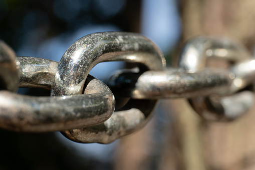 Close-up of the links of a metal chain in sunlight; selective focus; strength, connection and teamwork; bond