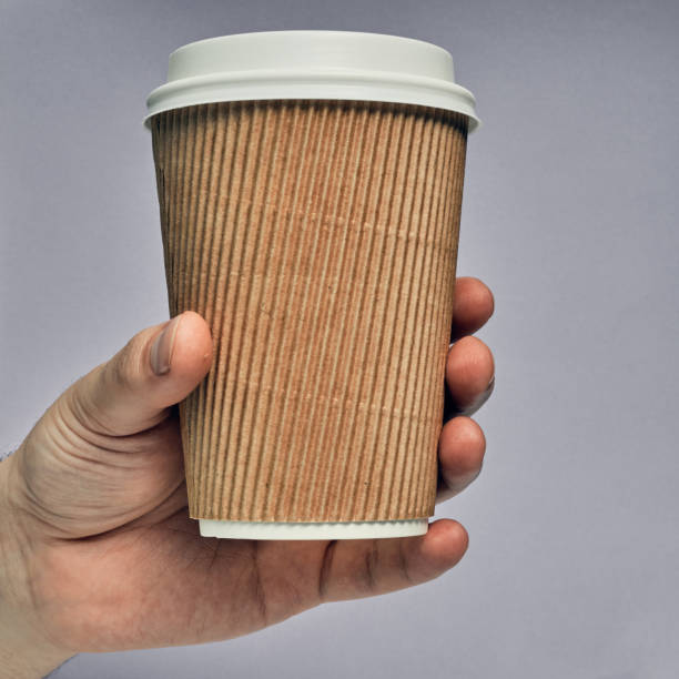 istock Paper cup in hand on a colored background. Eco-friendly materials in a coffee shop, biodegradable disposable tableware. Close up 1276868629