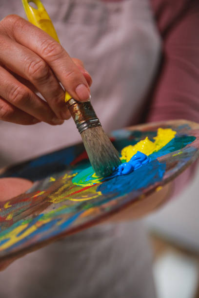 istock Woman making green paint by mixing yellow and blue 1276868690