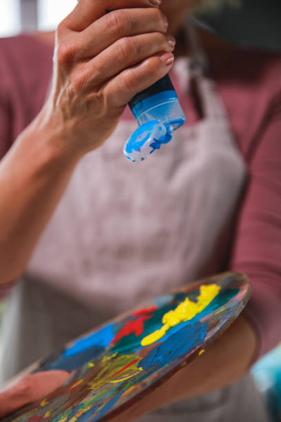 istock Woman adding blue paint on artist's palette 1276868696