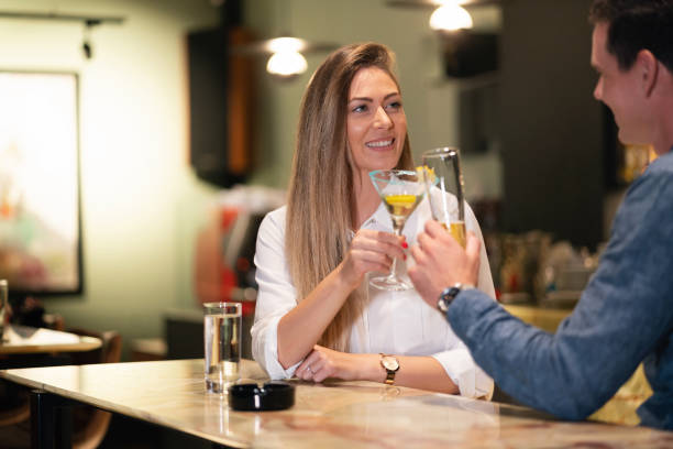 istock Young woman toasting with a young man in a bar at night 1276870132