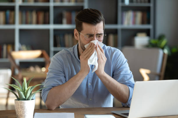 istock Sick man blow nose working at home workplace 1276876759