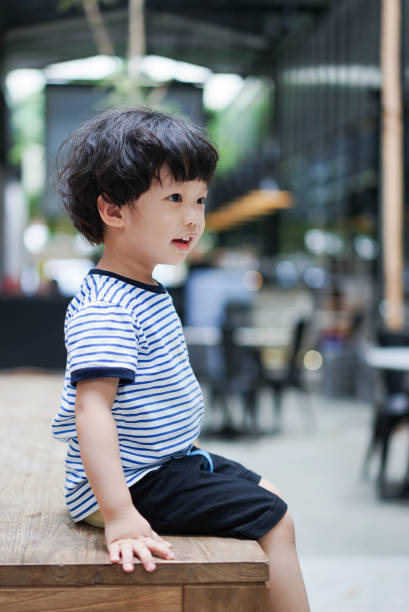 Adorable boy sitting on a wooden bench stock photo
