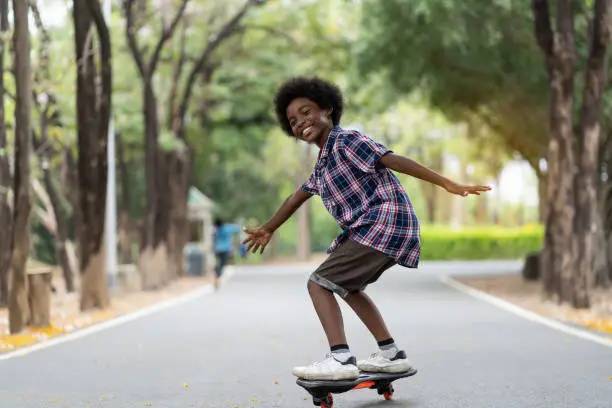 Photo of Happy child boy playing on roller blades, African American young boy riding on roller skates in the park, Kid playing on roller skates.