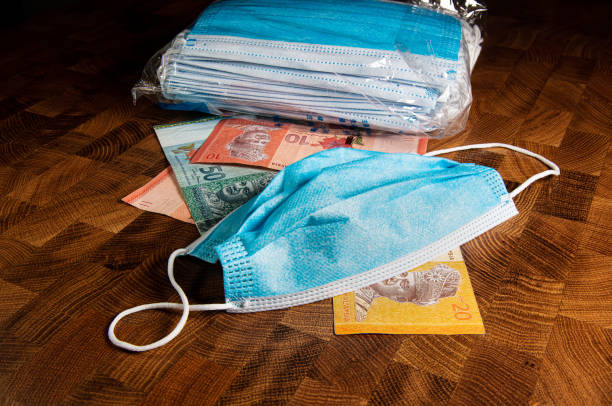 istock Face mask and banknotes on a wooden table 1276897109