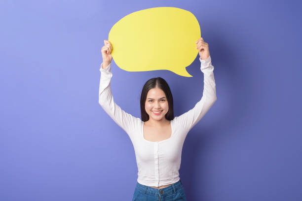 istock Young woman is holding yellow empty speech on purple background 1276902425