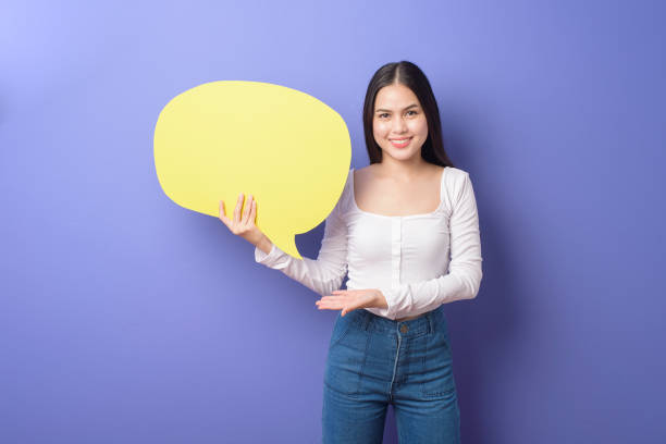 istock Young woman is holding yellow empty speech on purple background 1276902549