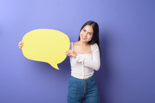 istock Young woman is holding yellow empty speech on purple background 1276902573
