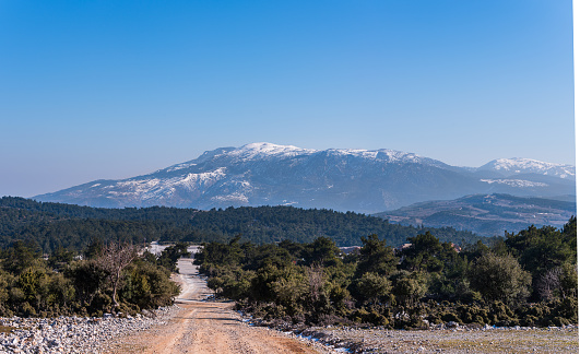 Landscape in the mountains. Dirt road, trees and Manisa Spil Mountain in the background.