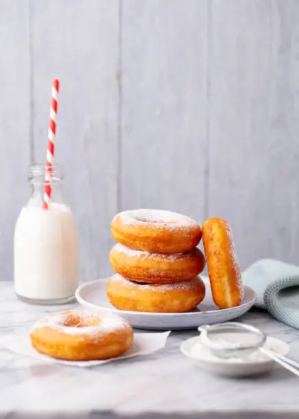 Photo of Donuts with bottle of milk on marble table. Grey background. Copy space.