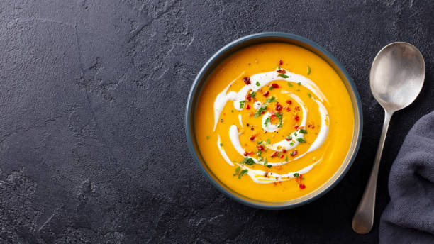 zuppa di zucca e carota con crema in ciotola nera. sfondo scuro. vista dall'alto. - soup pumpkin soup vegetarian food food foto e immagini stock