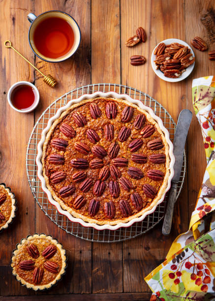 pecan pie, tart in baking dish. traditional festive thanksgiving dessert. wooden background. top view. - tart dessert tray bakery imagens e fotografias de stock