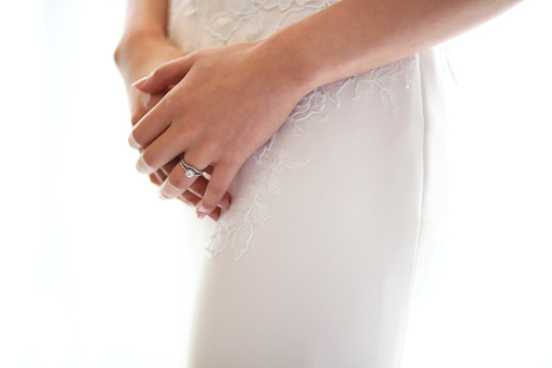 Midsection of a bride holding hands standing against white background