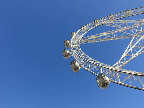 Low angle view Ferris wheel against blue sunny sky
