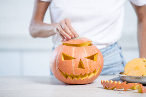 istock Orange halloween pumpkin with carved face in white kitchen 1276914406